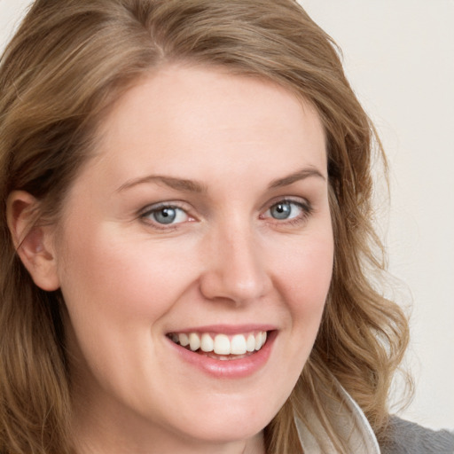 Joyful white young-adult female with long  brown hair and blue eyes