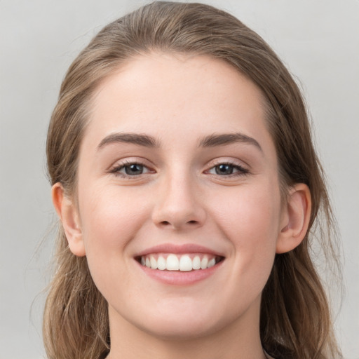 Joyful white young-adult female with long  brown hair and grey eyes