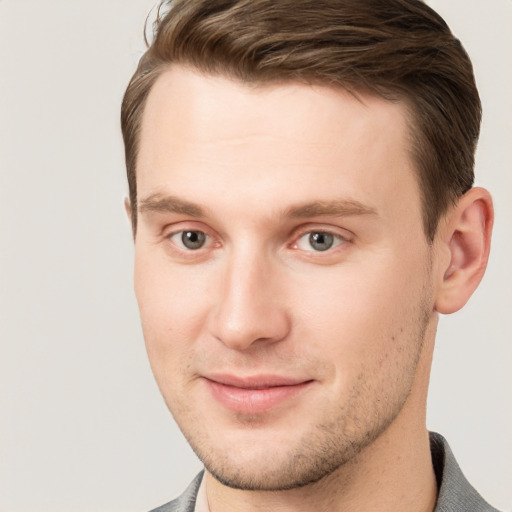 Joyful white young-adult male with short  brown hair and grey eyes