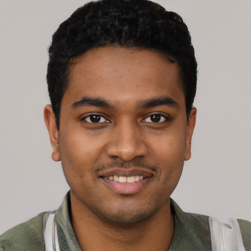 Joyful black young-adult male with short  black hair and brown eyes
