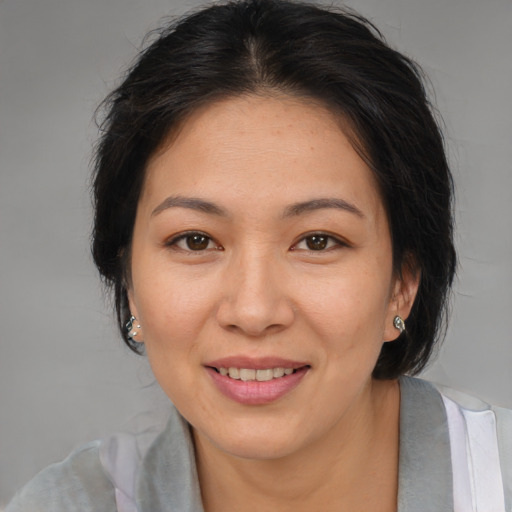 Joyful asian adult female with medium  brown hair and brown eyes