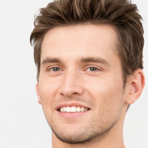 Joyful white young-adult male with short  brown hair and grey eyes