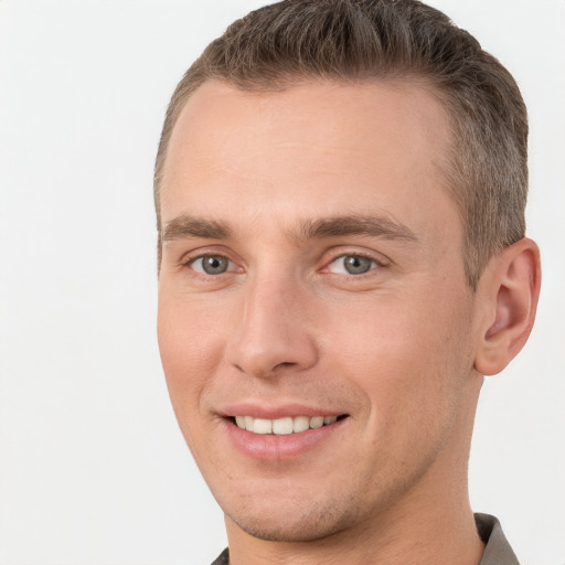 Joyful white young-adult male with short  brown hair and grey eyes