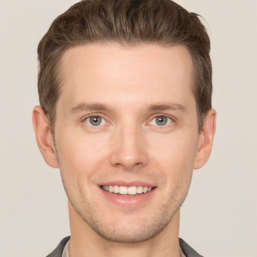 Joyful white young-adult male with short  brown hair and grey eyes