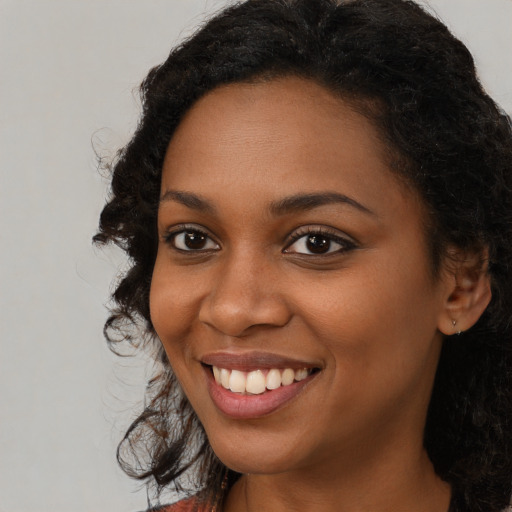 Joyful black young-adult female with long  brown hair and brown eyes