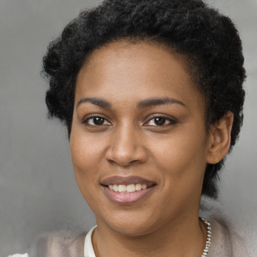 Joyful black young-adult female with short  black hair and brown eyes