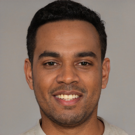 Joyful black young-adult male with short  black hair and brown eyes
