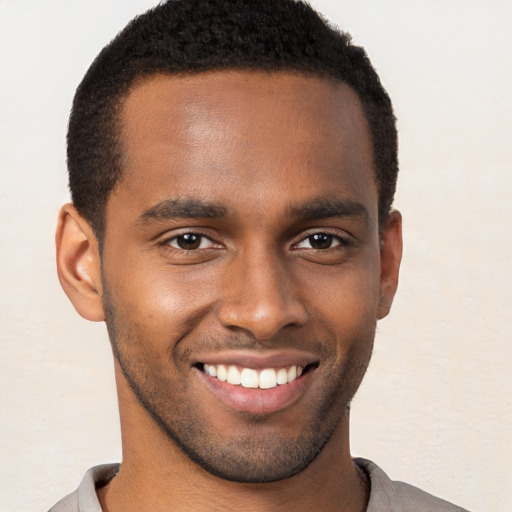 Joyful black young-adult male with short  brown hair and brown eyes