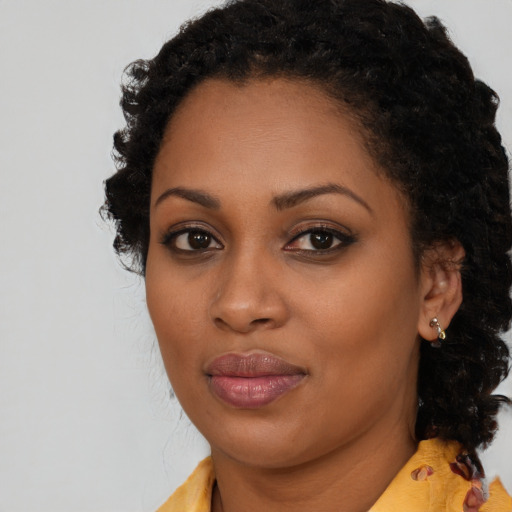 Joyful black young-adult female with long  brown hair and brown eyes