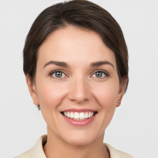 Joyful white young-adult female with short  brown hair and grey eyes