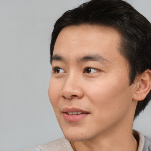 Joyful asian young-adult male with short  black hair and brown eyes