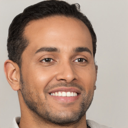 Joyful latino young-adult male with short  black hair and brown eyes