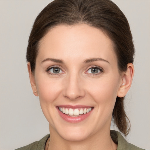 Joyful white young-adult female with medium  brown hair and grey eyes