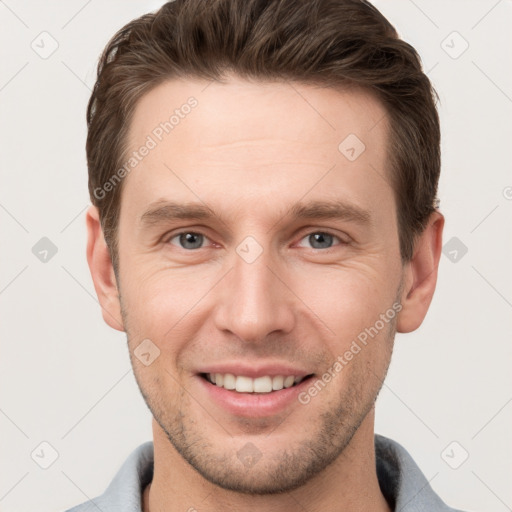 Joyful white young-adult male with short  brown hair and grey eyes