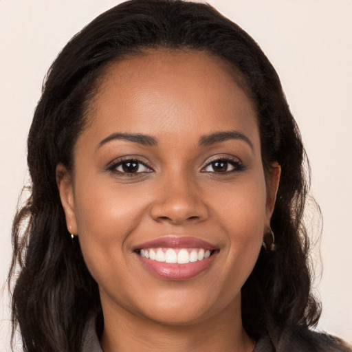 Joyful black young-adult female with long  brown hair and brown eyes