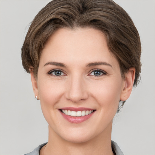 Joyful white young-adult female with short  brown hair and grey eyes