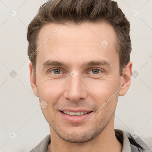 Joyful white young-adult male with short  brown hair and grey eyes