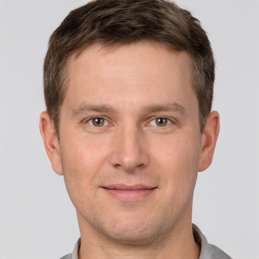 Joyful white young-adult male with short  brown hair and grey eyes