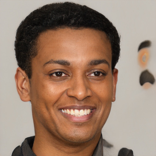 Joyful black young-adult male with short  brown hair and brown eyes