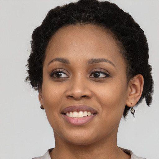 Joyful black young-adult female with short  black hair and brown eyes