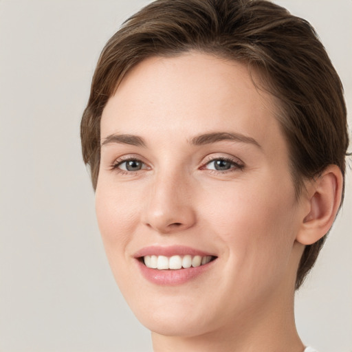 Joyful white young-adult female with short  brown hair and grey eyes