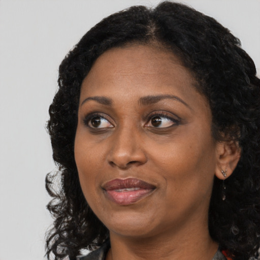 Joyful black adult female with long  black hair and brown eyes