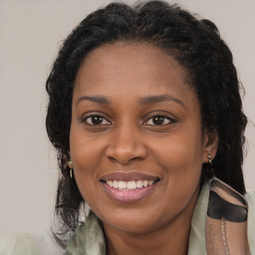 Joyful black young-adult female with long  brown hair and brown eyes