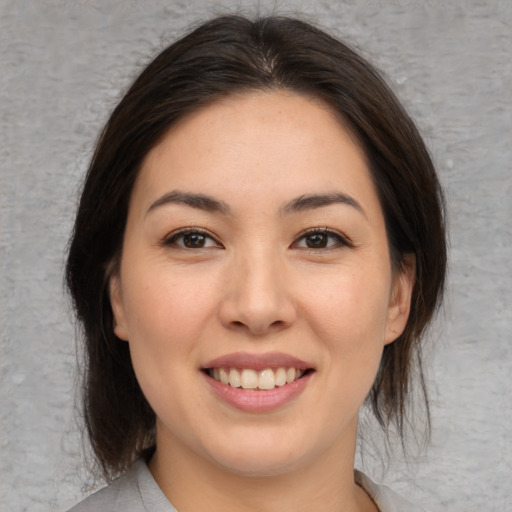 Joyful asian young-adult female with medium  brown hair and brown eyes