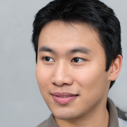 Joyful asian young-adult male with short  brown hair and brown eyes