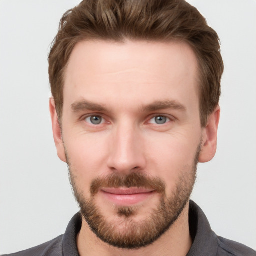 Joyful white young-adult male with short  brown hair and grey eyes