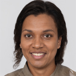 Joyful black adult female with long  brown hair and brown eyes