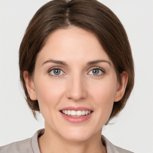 Joyful white young-adult female with medium  brown hair and grey eyes