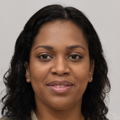 Joyful black young-adult female with long  brown hair and brown eyes