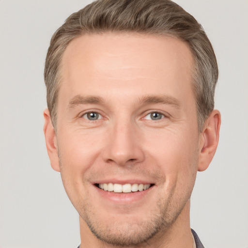 Joyful white young-adult male with short  brown hair and grey eyes