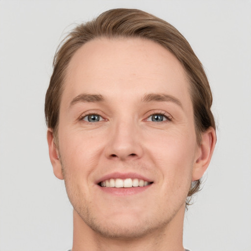 Joyful white young-adult male with short  brown hair and grey eyes