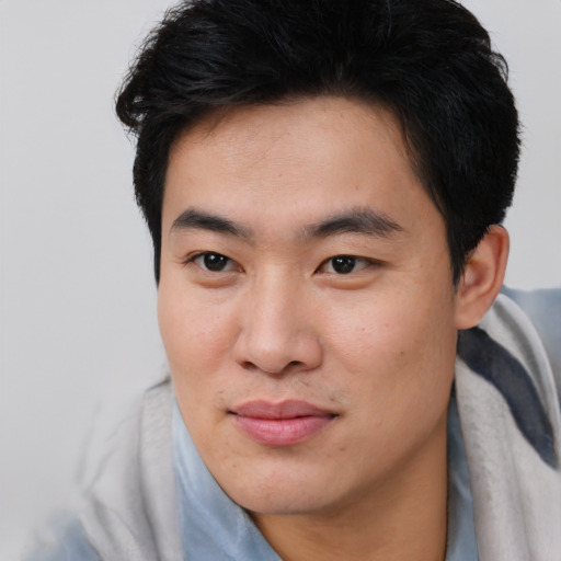 Joyful asian young-adult male with short  brown hair and brown eyes