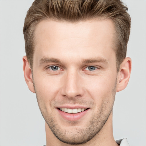 Joyful white young-adult male with short  brown hair and grey eyes