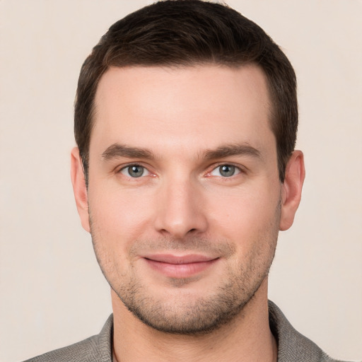 Joyful white young-adult male with short  brown hair and grey eyes