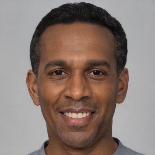 Joyful black adult male with short  black hair and brown eyes
