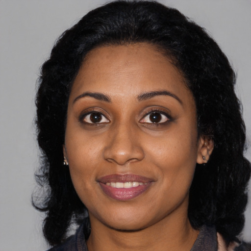 Joyful black young-adult female with long  black hair and brown eyes