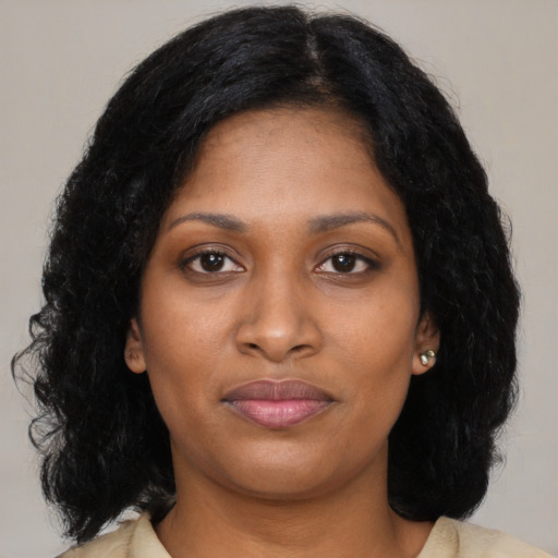 Joyful black young-adult female with long  black hair and brown eyes
