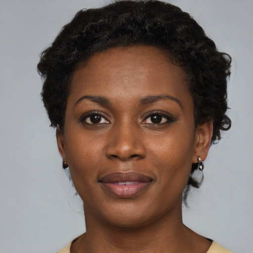 Joyful black young-adult female with short  black hair and brown eyes