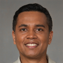 Joyful latino young-adult male with short  black hair and brown eyes