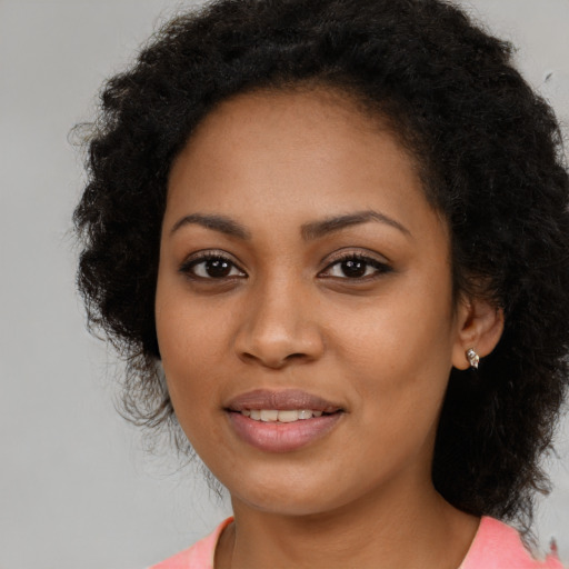 Joyful black young-adult female with long  black hair and brown eyes