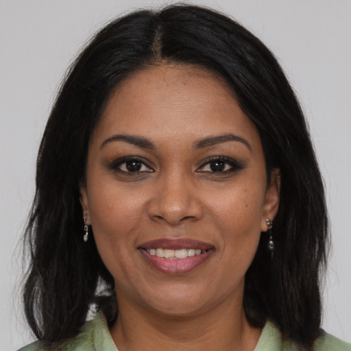 Joyful black young-adult female with long  brown hair and brown eyes