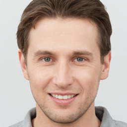 Joyful white young-adult male with short  brown hair and grey eyes