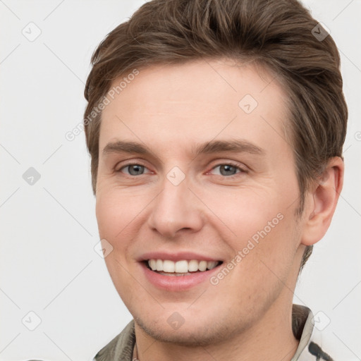 Joyful white young-adult male with short  brown hair and grey eyes