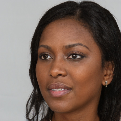 Joyful black young-adult female with long  brown hair and brown eyes