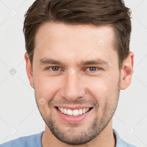 Joyful white young-adult male with short  brown hair and grey eyes