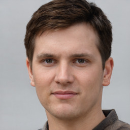 Joyful white young-adult male with short  brown hair and grey eyes